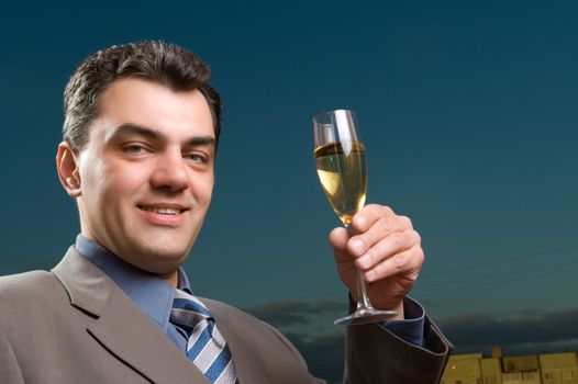 man in a suit against the evening sky with a glass of champagne