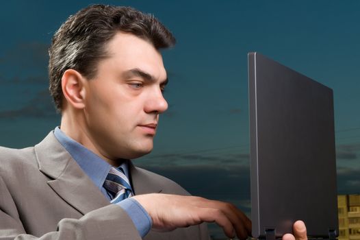 man in a suit against the evening sky with laptop