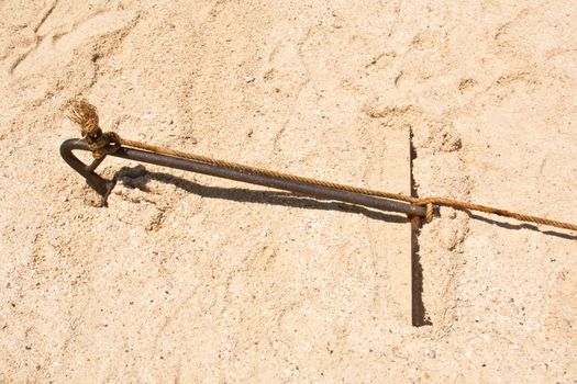 Old rusty anchor embroidered on the beach.