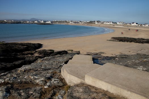 Concrete set of steps Trearddur bay beach, Anglesey, Wales, UK, with people in the distance.