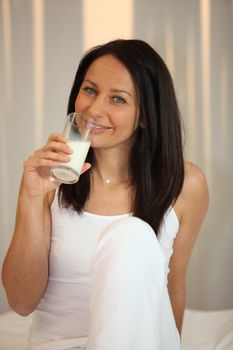 Woman in white drinking a glass of milk
