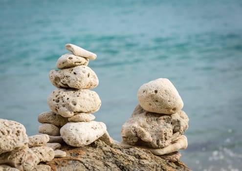 Multiple stacks of pebbles on rock by sea shore with sun lighting the piles