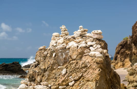 Multiple stacks of pebbles on rock by sea shore with sun lighting the piles