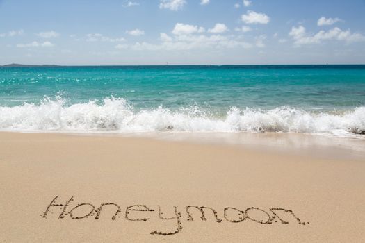 Honeymoon words written into sand on beach by sea in St Thomas
