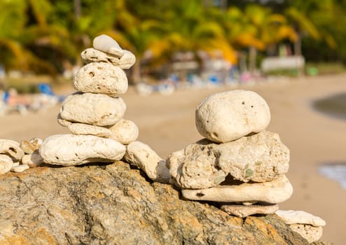 Multiple stacks of pebbles on rock by sea shore with sun lighting the piles