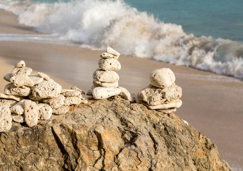 Multiple stacks of pebbles on rock by sea shore with sun lighting the piles