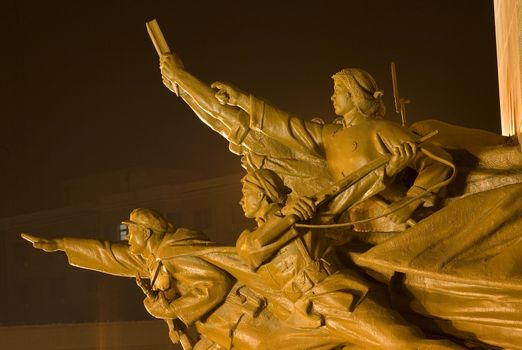 Mao Zedong Statue with Heroes Zhongshan Square Shenyang, Liaoning Province, China at Night.  Built in 1969 during the Cultural Revolution.  The hero is holding a copy of Mao Zedong Thought