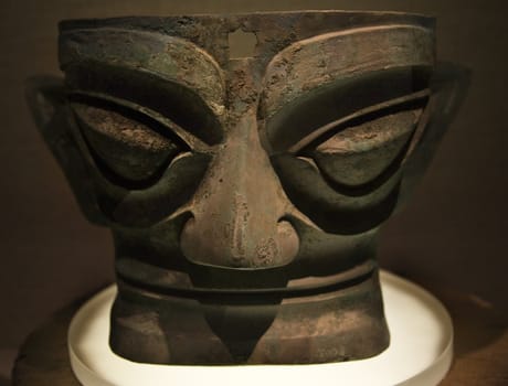 Large Dark Bronze Mask Statue Sanxingdui Three Star Mound Museum Guanghan Chengdu Sichuan China The mask is 3,000 years old and was discoved in the vicitinity of the museum.  The statues have been carbon dated to the 11th-12th Century BCE.