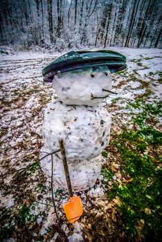 Dirty snowman made of snow and leaves in the backyard