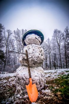 Dirty snowman made of snow and leaves in the backyard