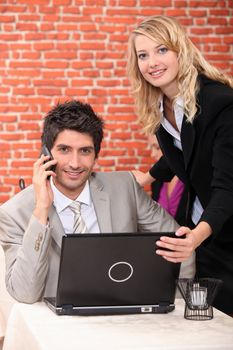 Man using a laptop and mobile phone in a restaurant