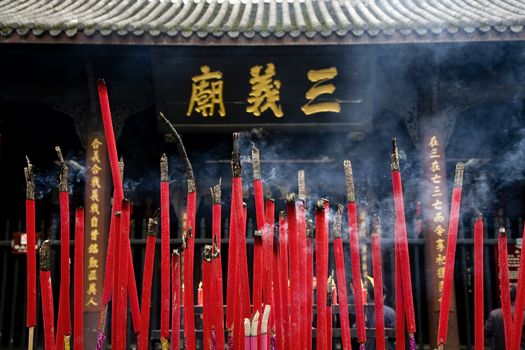 Burning Incense Ancient Chinese Temple of Three Kingdoms, Wuhou Memorial, Chengdu, Sichuan, China.  The three Chinese characters are not a trademark.  They stand for the three kingdoms and the famous historical novel Romance of the Three Kingdoms.  This Temple Was Last Rebuilt in the 1600s.