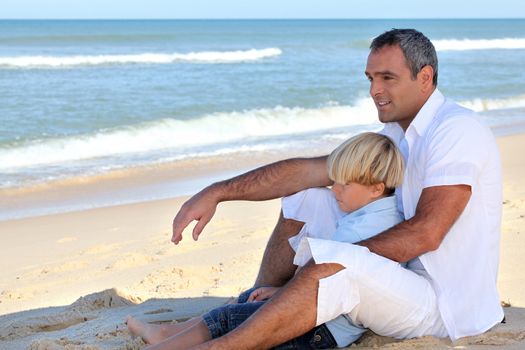 Father and son sitting on a beach