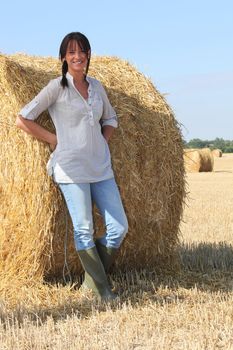 Woman in wellington boots standing in a field of hay
