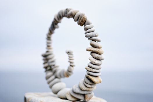 White spiral of pebbles on the boulder at the sea