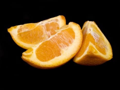 Three pieces of very juicy orange on black background