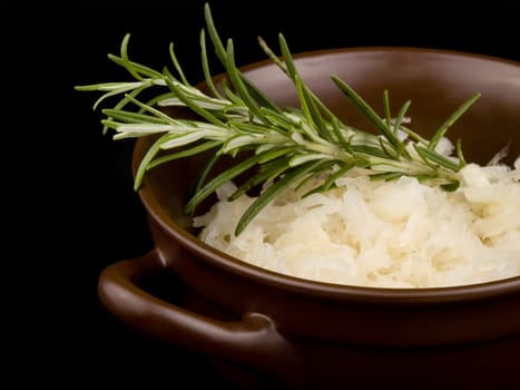 Ceramic bowl filled with sour cabbage on black background