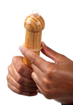 Female hands wrap a condom over a wooden penis to show how it is used.