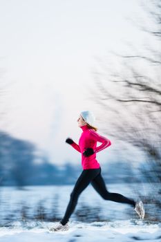 Young woman running outdoors on a cold winter day (motion blurred image)