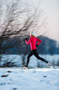 Young woman running outdoors on a cold winter day (motion blurred image)