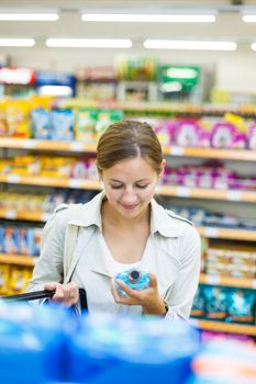 Beautiful young woman shopping in a grocery store/supermarket (color toned image)