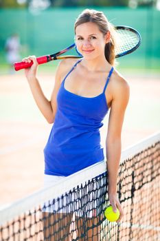Portrait of a pretty young tennis player on the court
