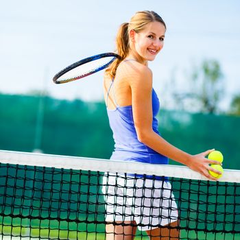 Portrait of a pretty young tennis player on the court