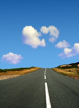 Country road leads towards blue cloudy sky