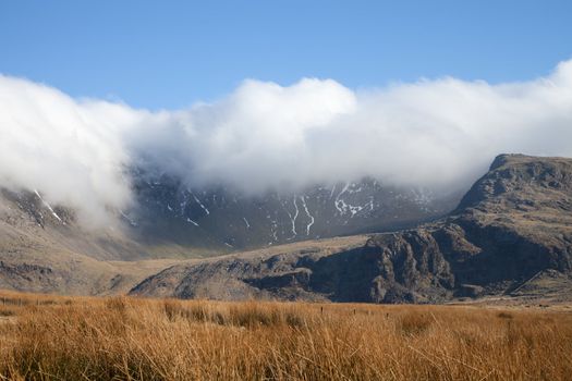 A sunny day with clouds inverting over the summit of mount Snowdon, Snowdonia national park, Wales, UK.