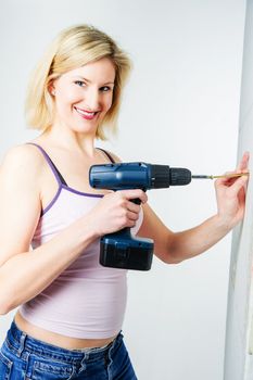 Blonde woman driving an Screw into a Wall