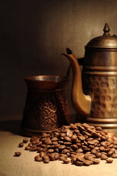 Vintage still life with heap of coffee beans near old copper coffeepot