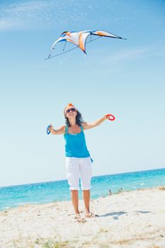 Young cute woman playing with a colorful kite on the tropical beach. Vertikal veiw