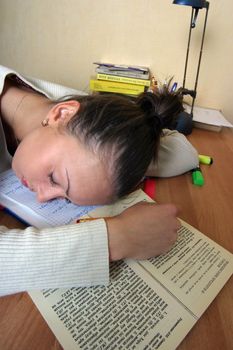 The attractive girl has fallen asleep behind preparation for examinations