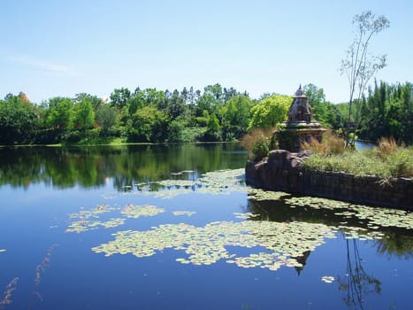 A lake / river with lily pads and trees in the background