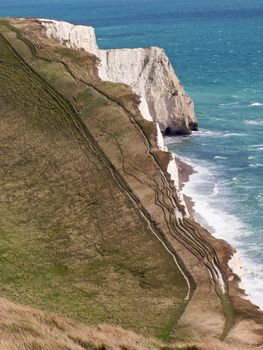 A steep descent and ascent on the Dorset coastline. Due to erosion, the coastal path is now precariously close to the cliff edge.