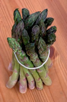 A bundle of asparagus tied up on a wooden work surface