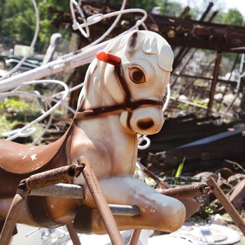 Old abandoned playground toy horse in junkyard.