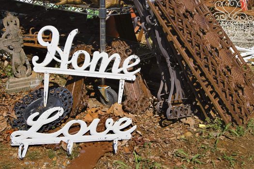 Metal garden decorations of words Love and Home next to rusted metal objects.