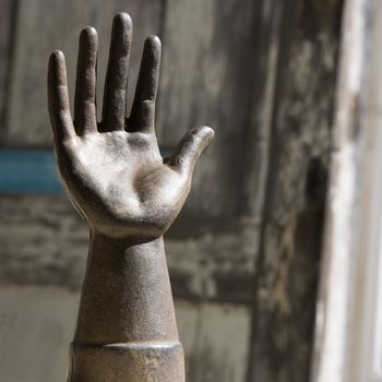 Metal statue of hand against wooden background.