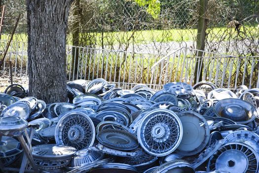 Stacks of old hubcaps on the ground next to tree.