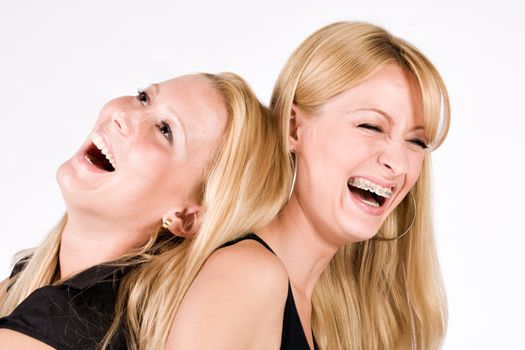 Two sisters sitting back to back laughing out loud