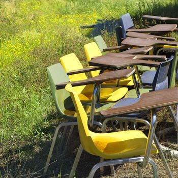 Old school chairs in grassy field.