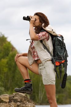 The girl with a backpack which looks in the field-glass