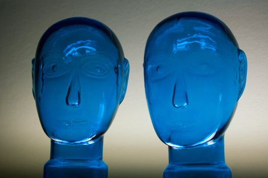 Two glass dark blue heads on a neutral background