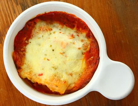 Small baked lasagna on rustic background.