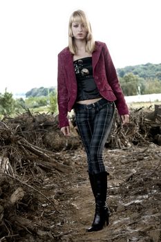 Fashion shoot of a woman. She is walking amond dead tree stumps