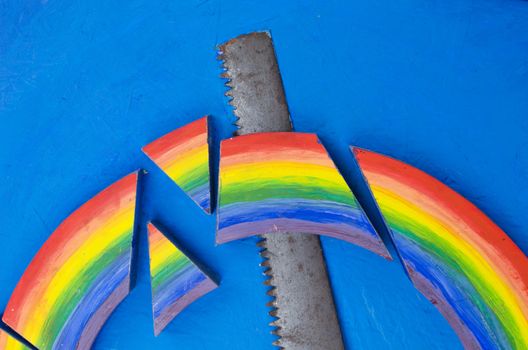 colorful rainbow cut with retro hand saw on blue background concept.
