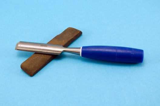 chisel graver carve tool for wood work and whetstone stone on blue background.