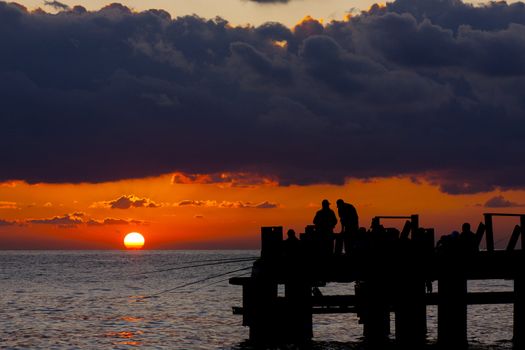 Fishermans on a pier in the evening on a sea