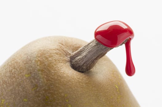 Green pear with red sealing wax on stalk